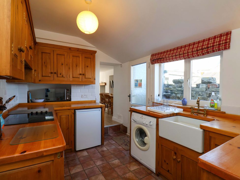 A kitchen with wooden cabinets and appliances at Cozy Cottage in 