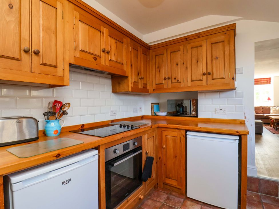 A kitchen with wooden cabinets and appliances at Cozy Cottage