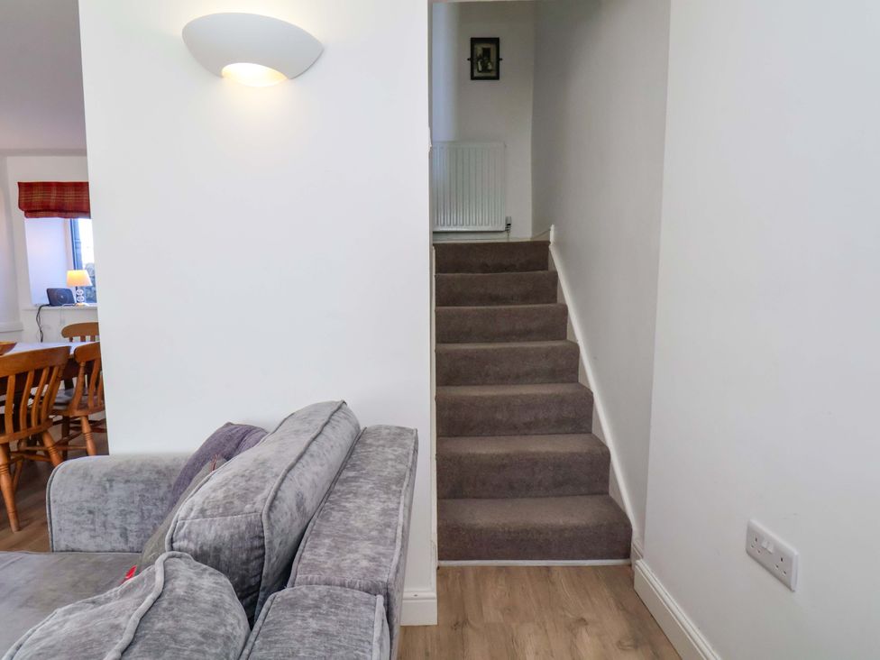 A living room with a staircase and dining area at Cozy Cottage