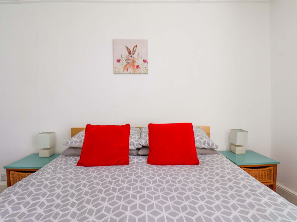 A bed with red cushions and lamps in a bedroom at Cozy Cottage