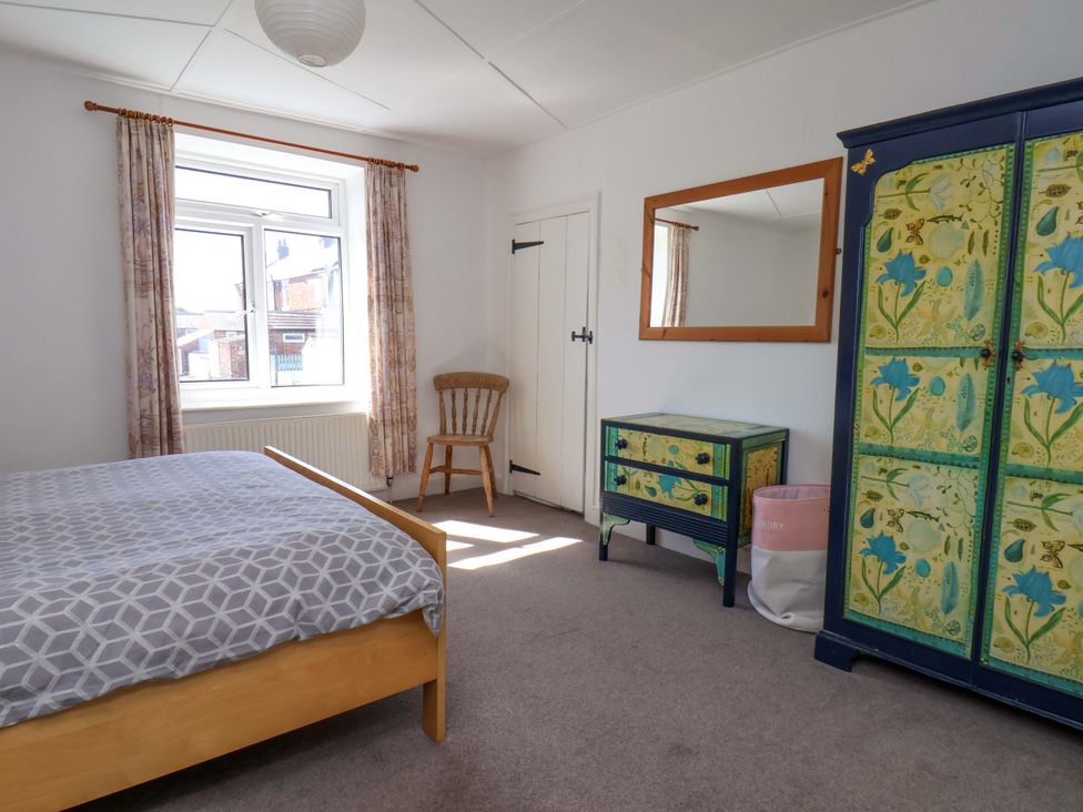 A bedroom with a bed, chair, and wardrobe at Cozy Cottage