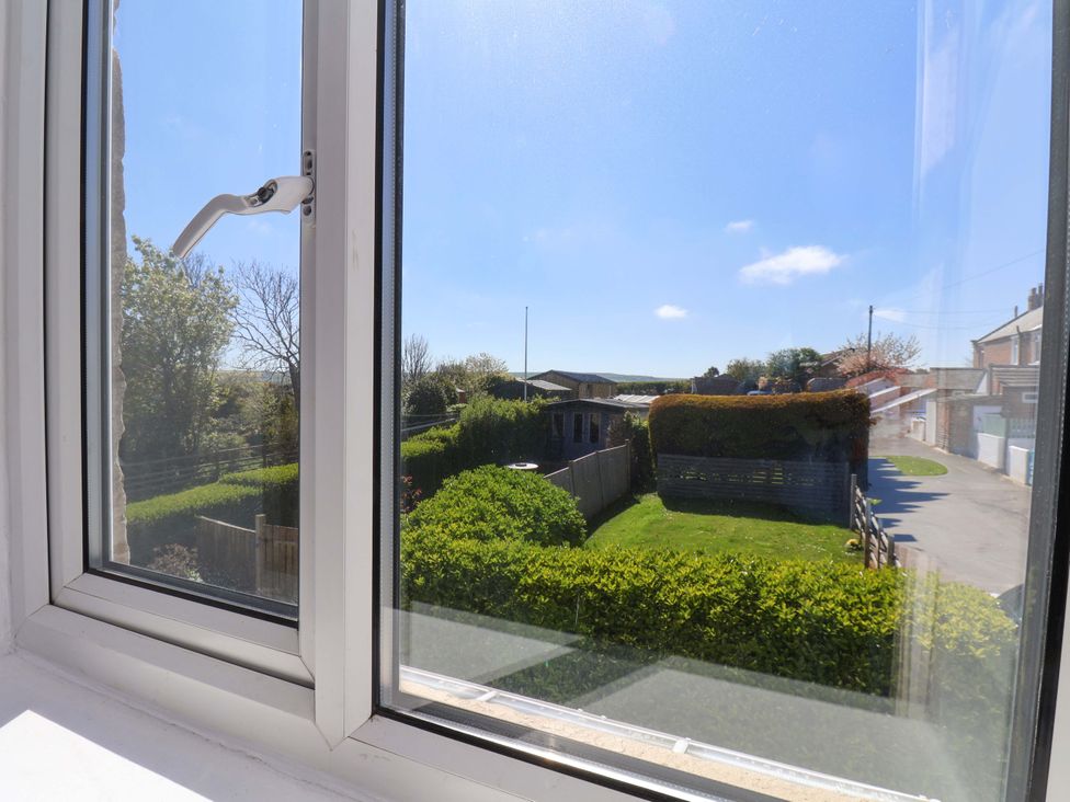 A view of a garden with hedges and a fence from a window at Cozy Cottage