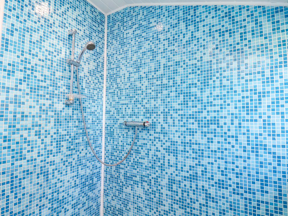 A shower with blue mosaic tiles at Cozy Cottage