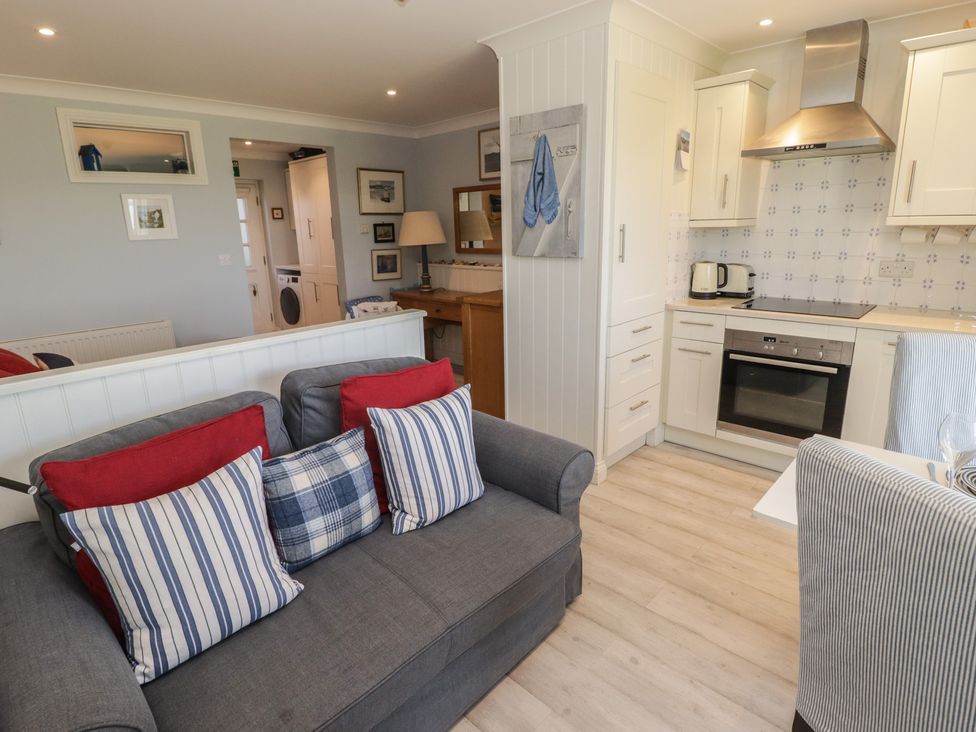 A living room with a sofa and kitchen area at The Bolthole in Newport