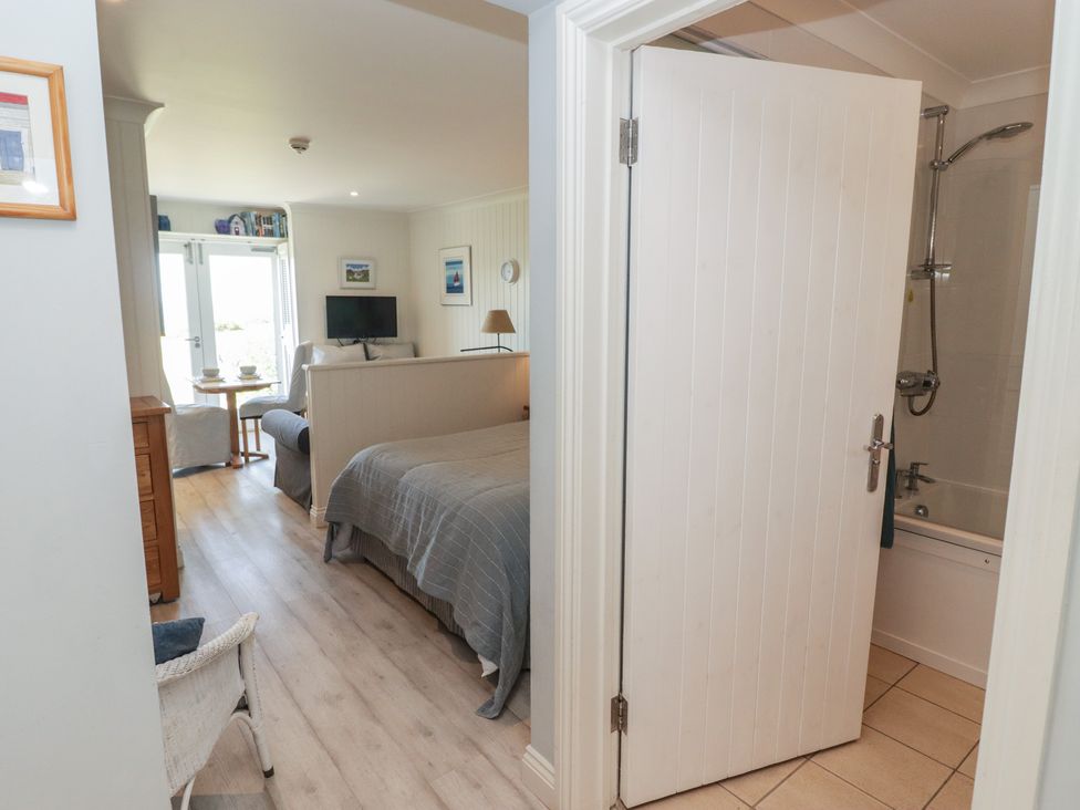 A bedroom with a bed, tv and door leading to a bathroom at The Bolthole in Newport