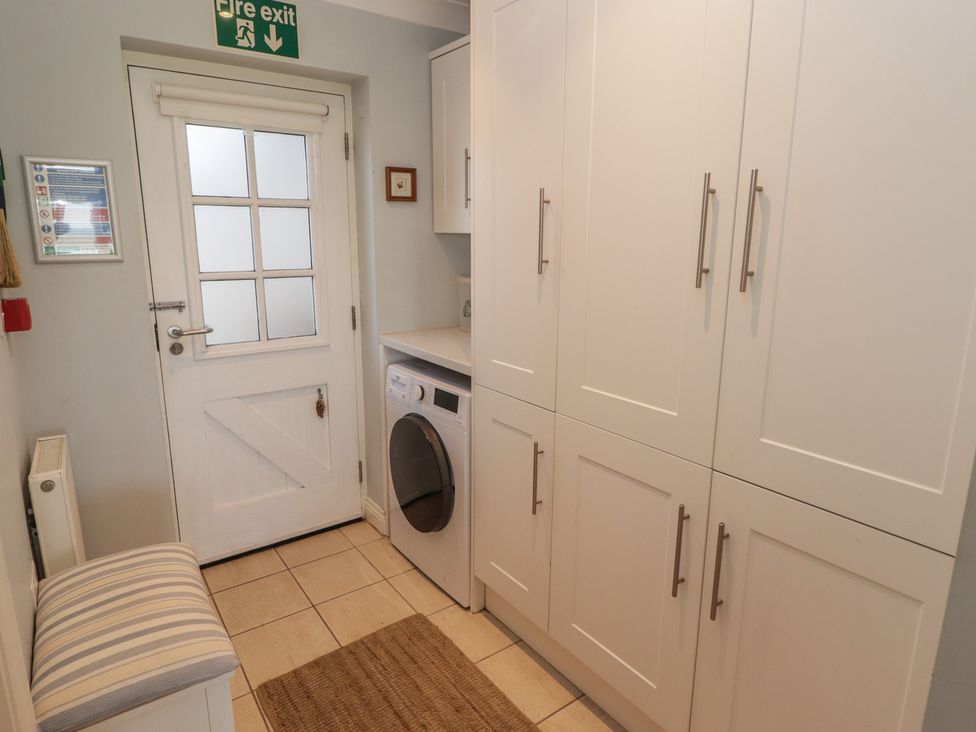 A laundry room with a washer and storage cabinets at The Bolthole in Newport
