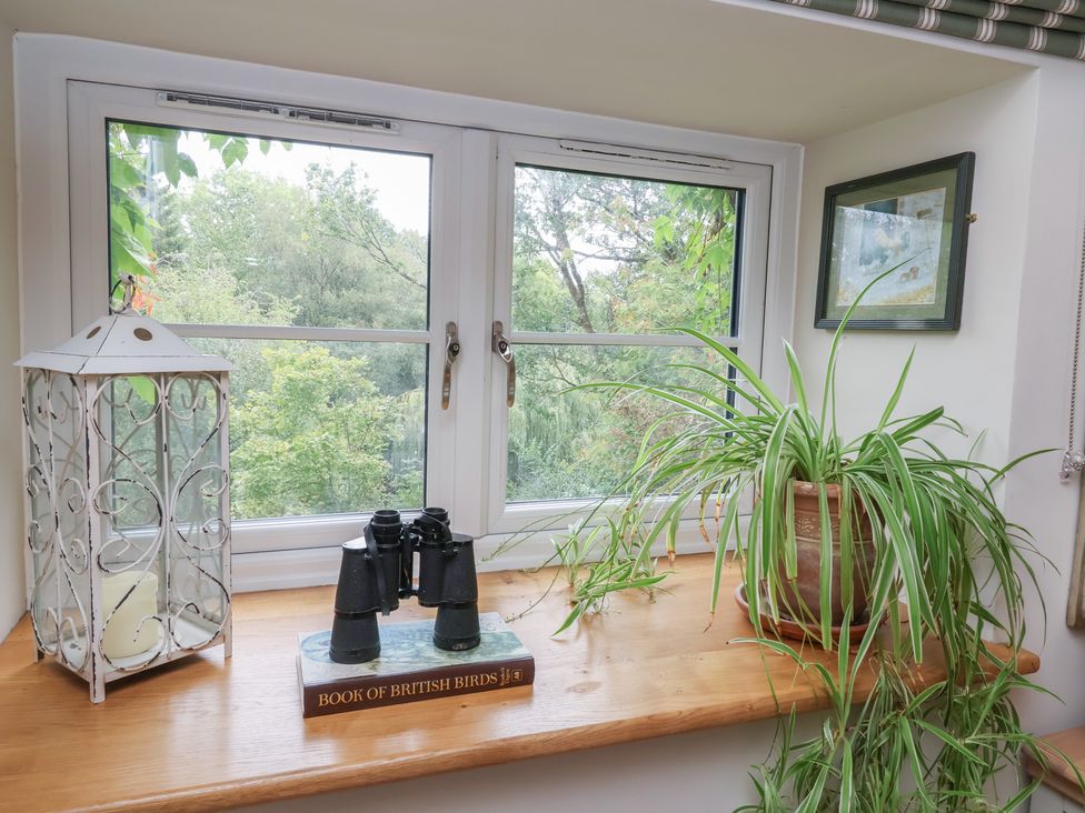 A window with binoculars and a book at The Bothy at Lewis Cottage in Spreyton