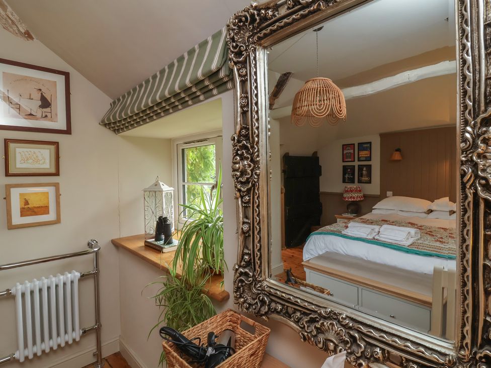 A bedroom showing a mirror and a bed at The Bothy at Lewis Cottage Spreyton