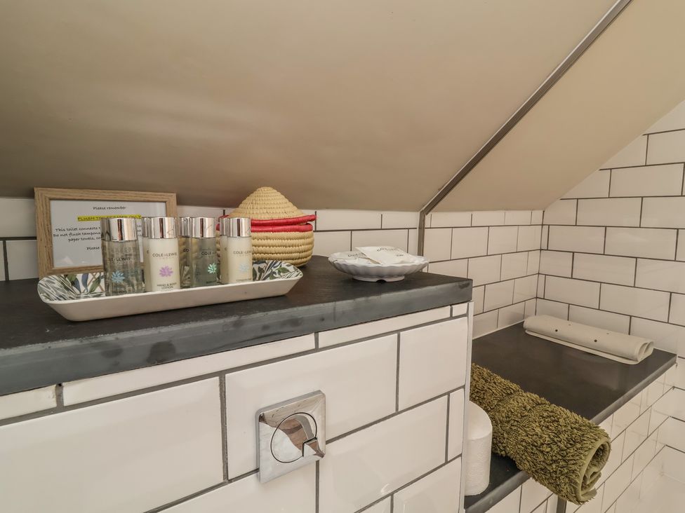 A bathroom countertop with toiletries and a towel at The Bothy at Lewis Cottage in Spreyton
