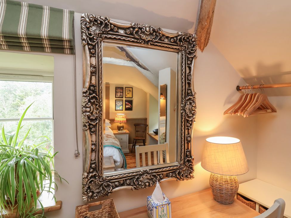 A bedroom with a mirror and a lamp at The Bothy at Lewis Cottage in Spreyton