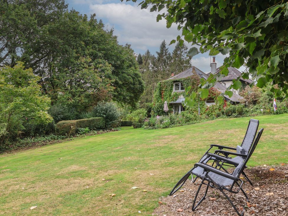 A garden with chairs and a house at The Bothy at Lewis Cottage Spreyton