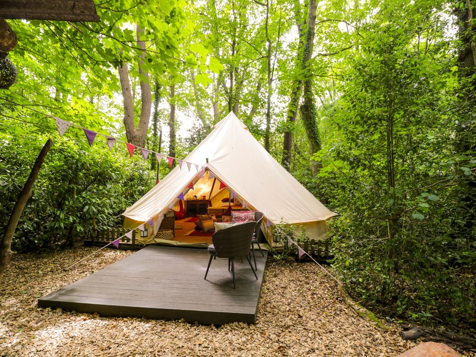A bell tent with a wooden deck and chairs at Bedouin Bell Tent Woolton Hill