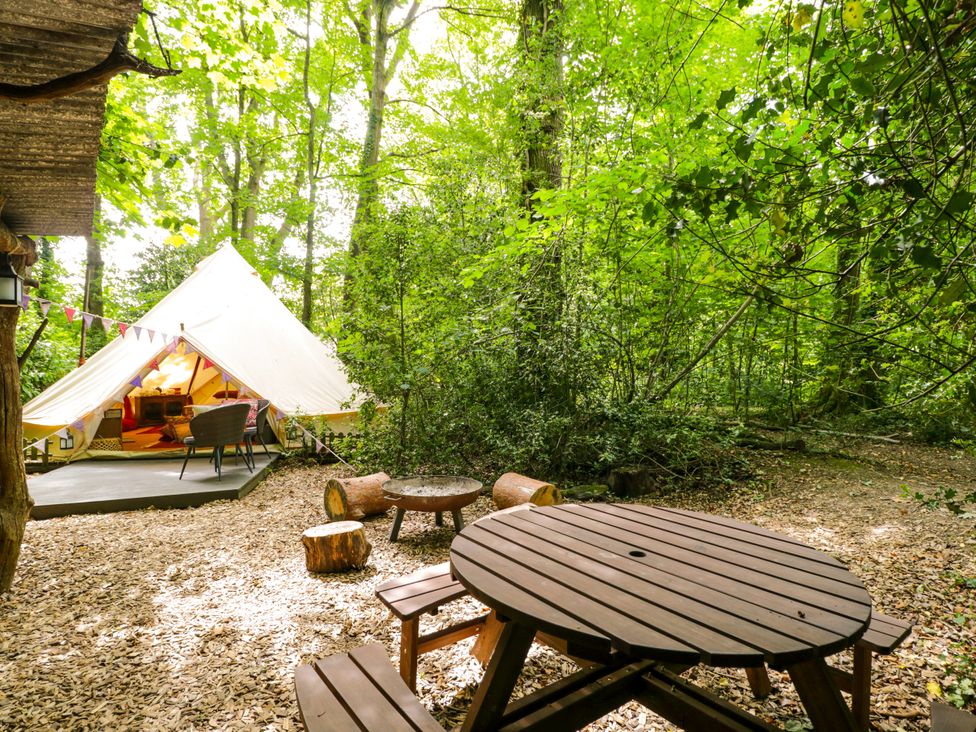 An outdoor area with a tent, table, and seating at Bedouin Bell Tent in Woolton Hill