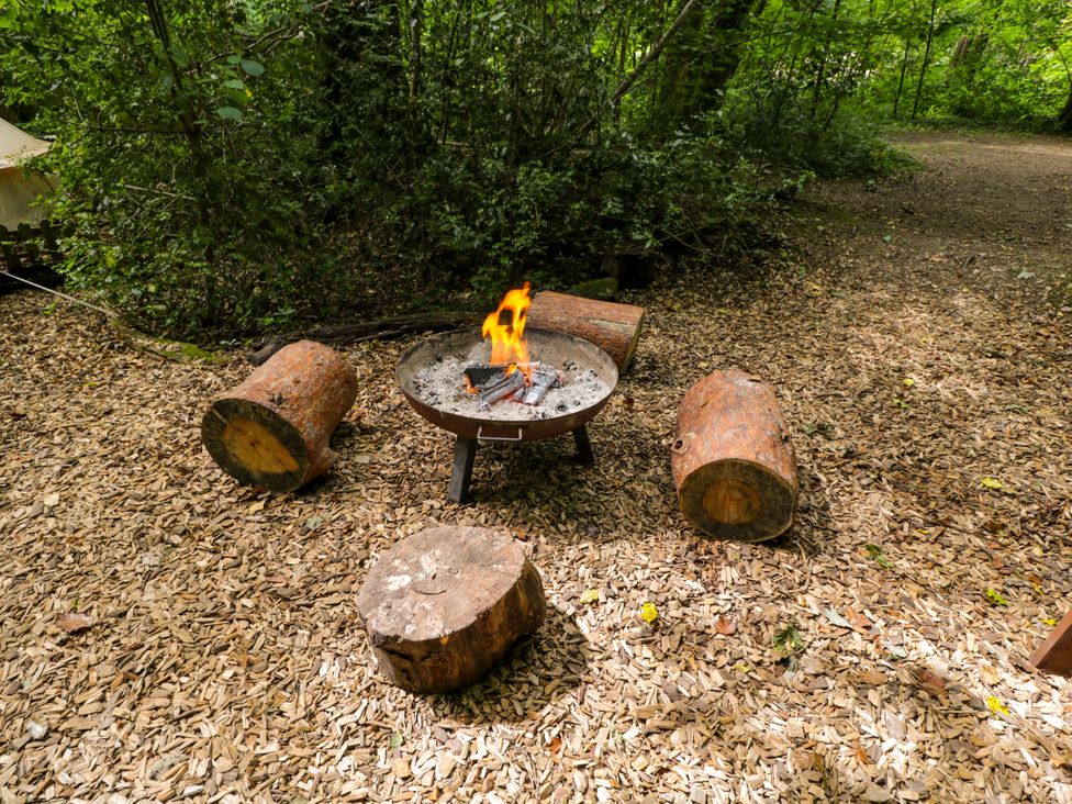 An outdoor area with a fire pit and logs at Bedouin Bell Tent in Woolton Hill