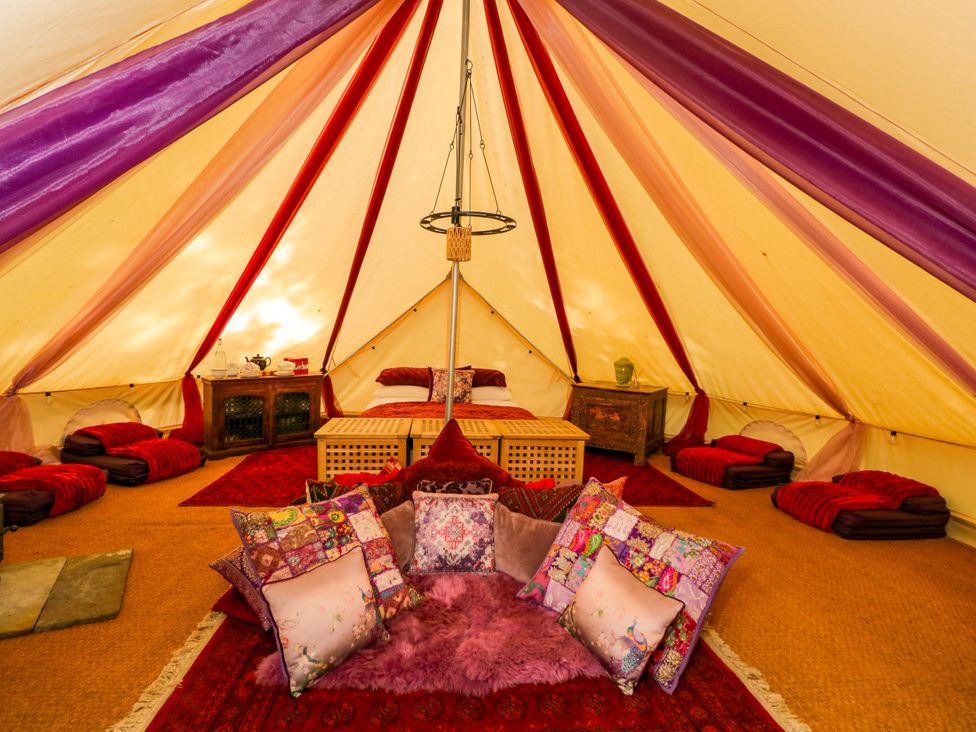 A tent with pillows and a table at Bedouin Bell Tent in Woolton Hill