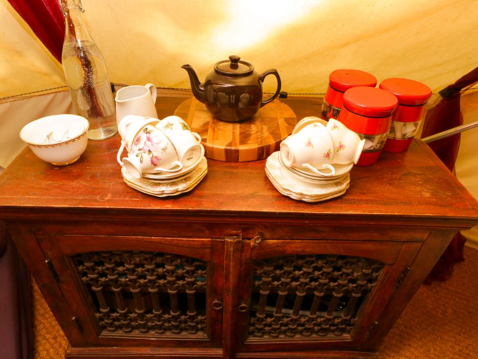 A wooden cabinet with teapot and teacups at Bedouin Bell Tent Woolton Hill