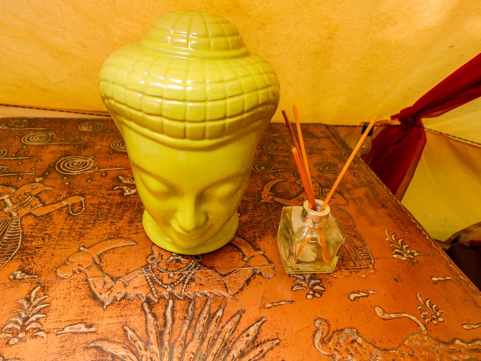 A green vase and a reed diffuser on a decorative table at Bedouin Bell Tent Woolton Hill