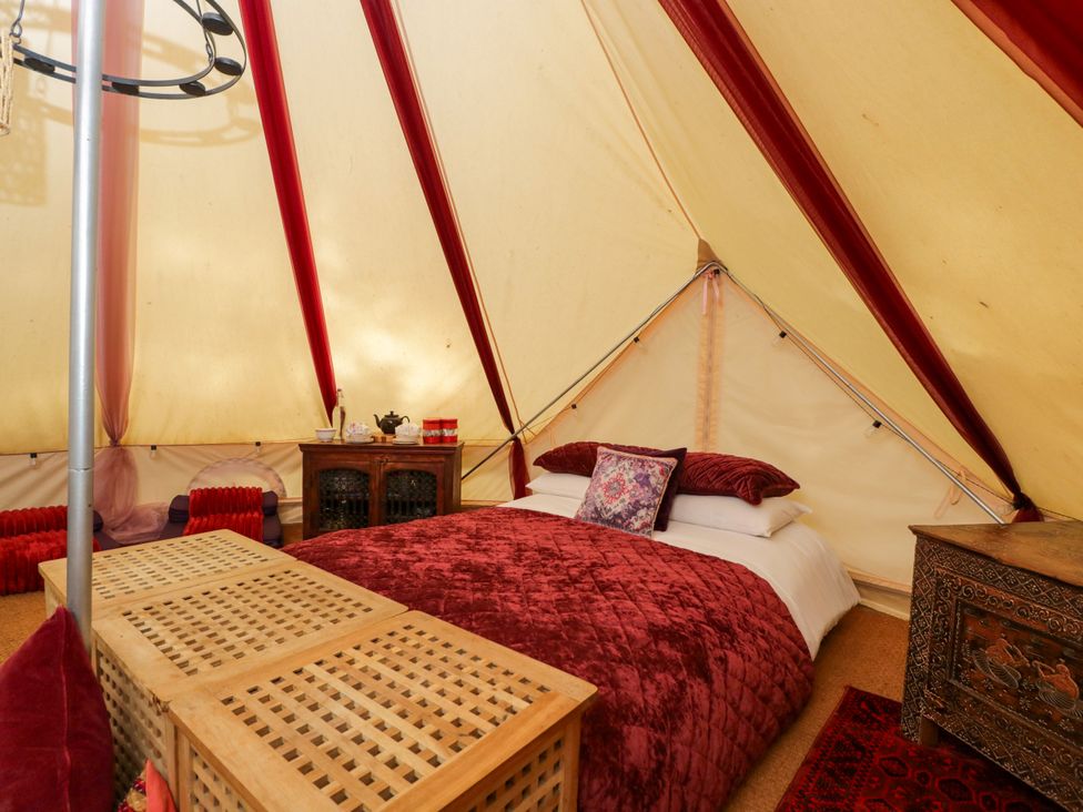 A bedroom with a bed and wooden table at the Bedouin Bell Tent in Woolton Hill