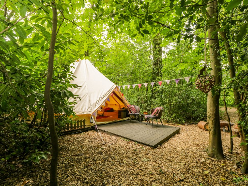 A bell tent with chairs and a table in an outdoor area at Bedouin Bell Tent in Woolton Hill