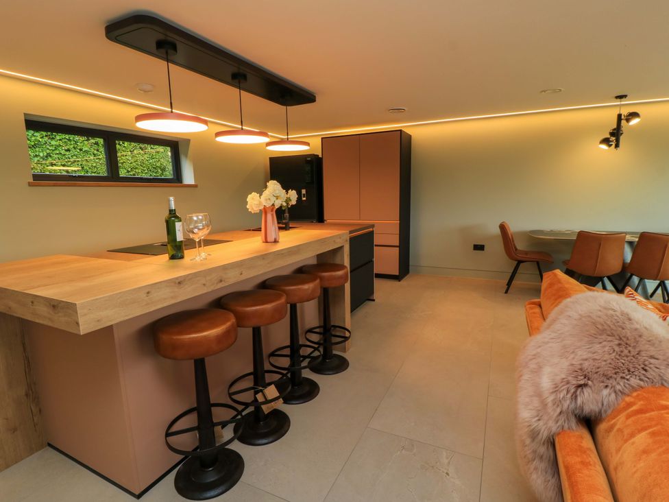 A kitchen with a bar area and stools at The Cozy Sow in Yeovil
