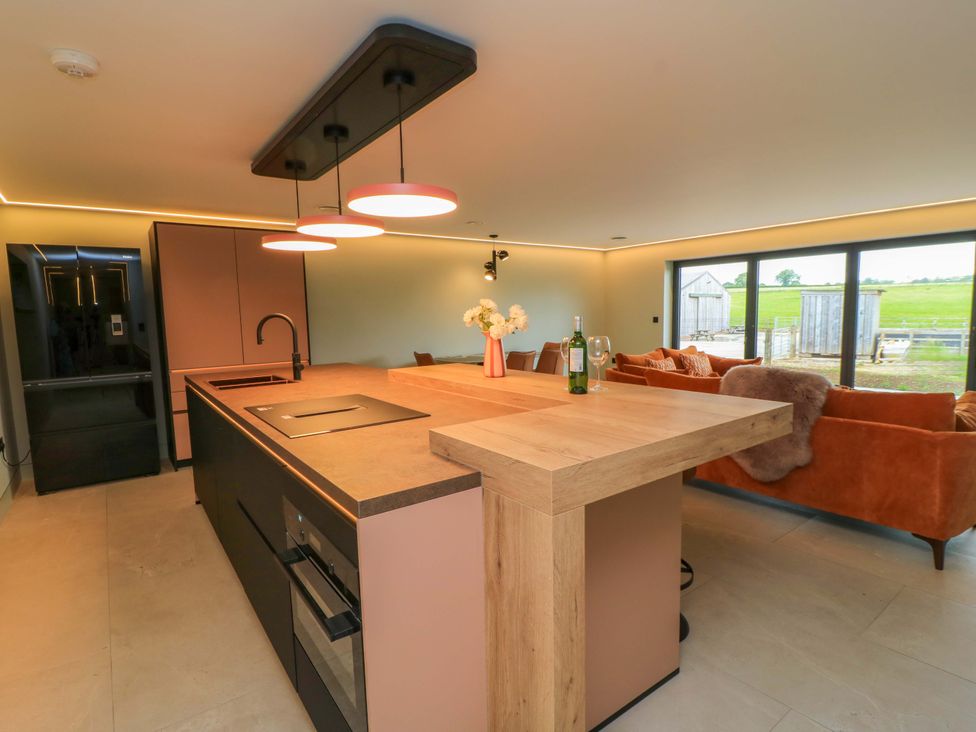 A kitchen with an island, refrigerator and sofa at The Cozy Sow in Yeovil