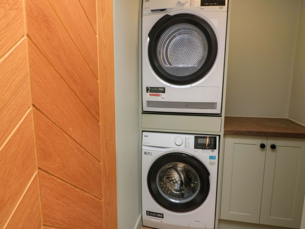 A laundry room featuring stacked washing machine and dryer at The Cozy Sow in Yeovil