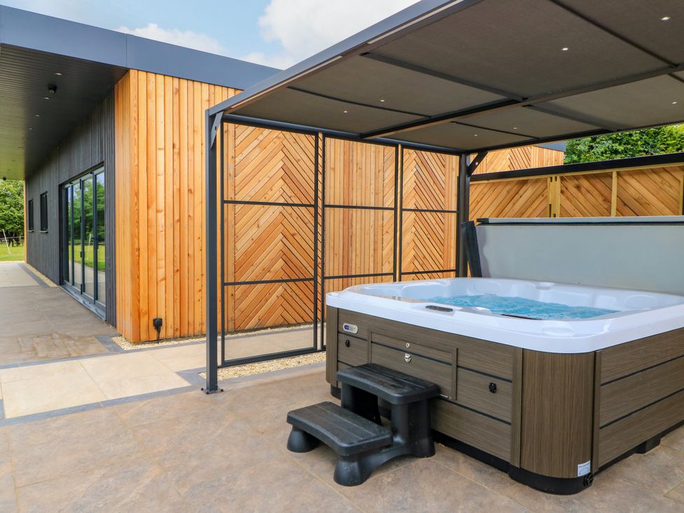 A hot tub with steps and wooden wall at The Cozie Sow in Galhampton