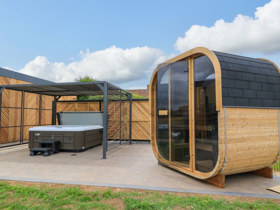 An outdoor spa area with a hot tub and wooden sauna at The Cozie Sow in Galhampton