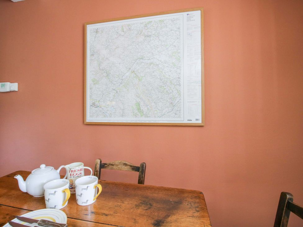 A dining room with a map on the wall and a table set with a teapot and mugs at Little Pentwyn in Clyro