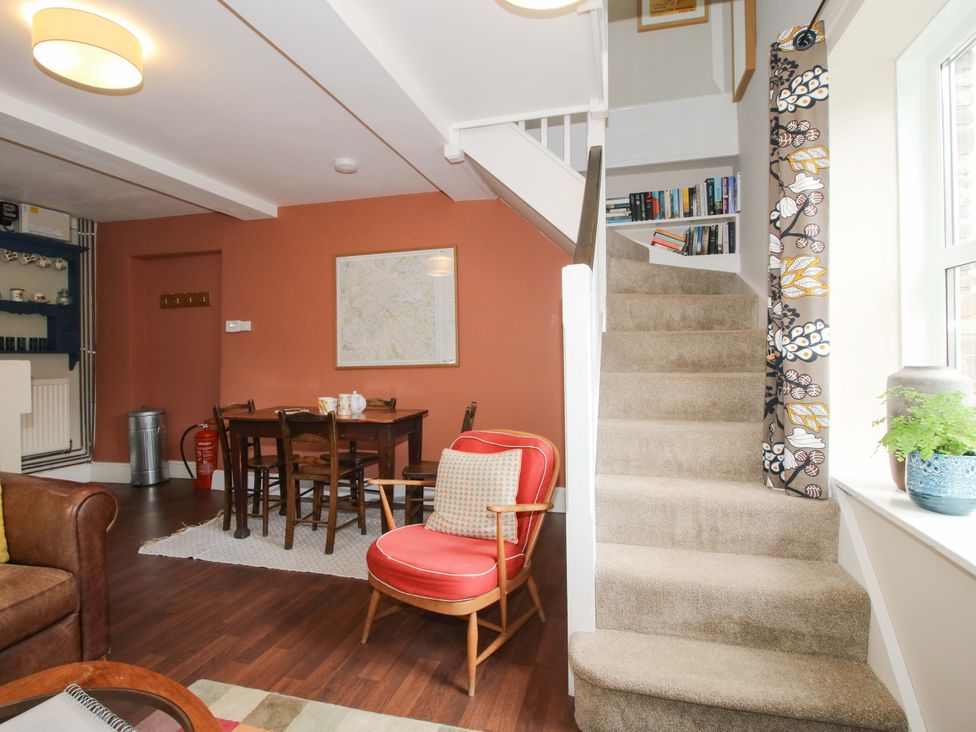 A living room with a dining table and staircase at Little Pentwyn in Clyro