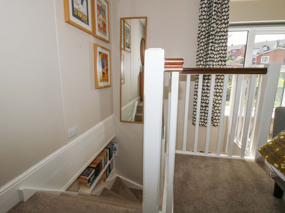 A staircase with a bookshelf and wall art in the hallway at Little Pentwyn Clyro
