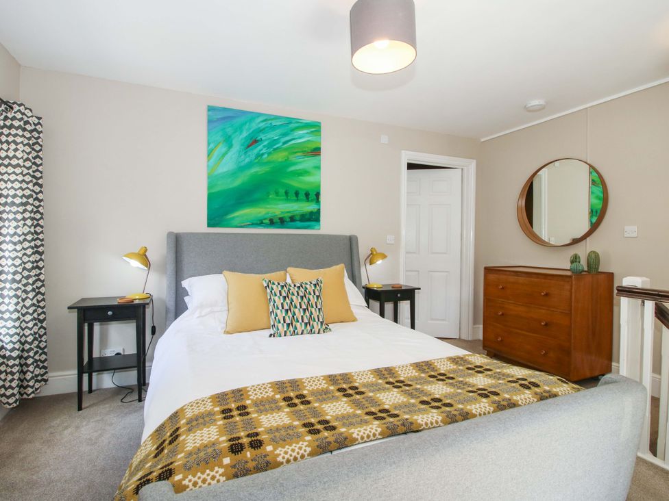 A bedroom with a bed, bedside table, and a painting at Little Pentwyn in Clyro