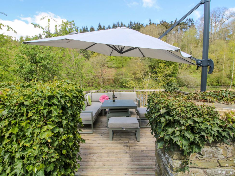 An outdoor seating area with a table and chairs under a parasol at Little Pentwyn in Clyro