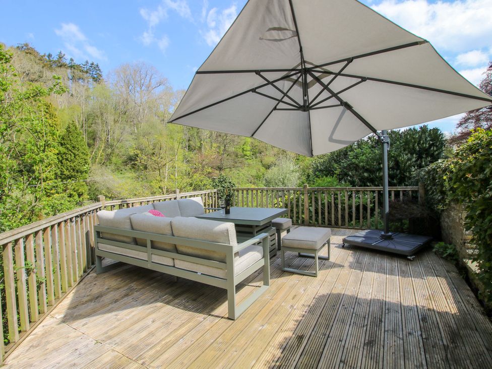 A deck with outdoor furniture and a sun umbrella at Little Pentwyn in Clyro