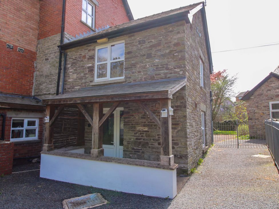 A stone building with a porch and gravel driveway at Little Pentwyn in Clyro