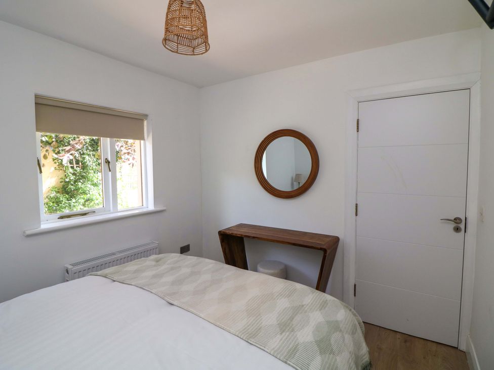 A bedroom with a bed, window, mirror, and table at The Mews @ Derrybawn Laragh, County Wicklow