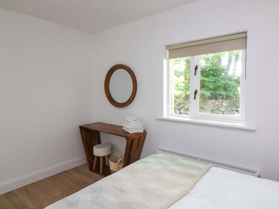A bedroom with a bed, table, mirror, and window at The Mews @ Derrybawn, Laragh, County Wicklow