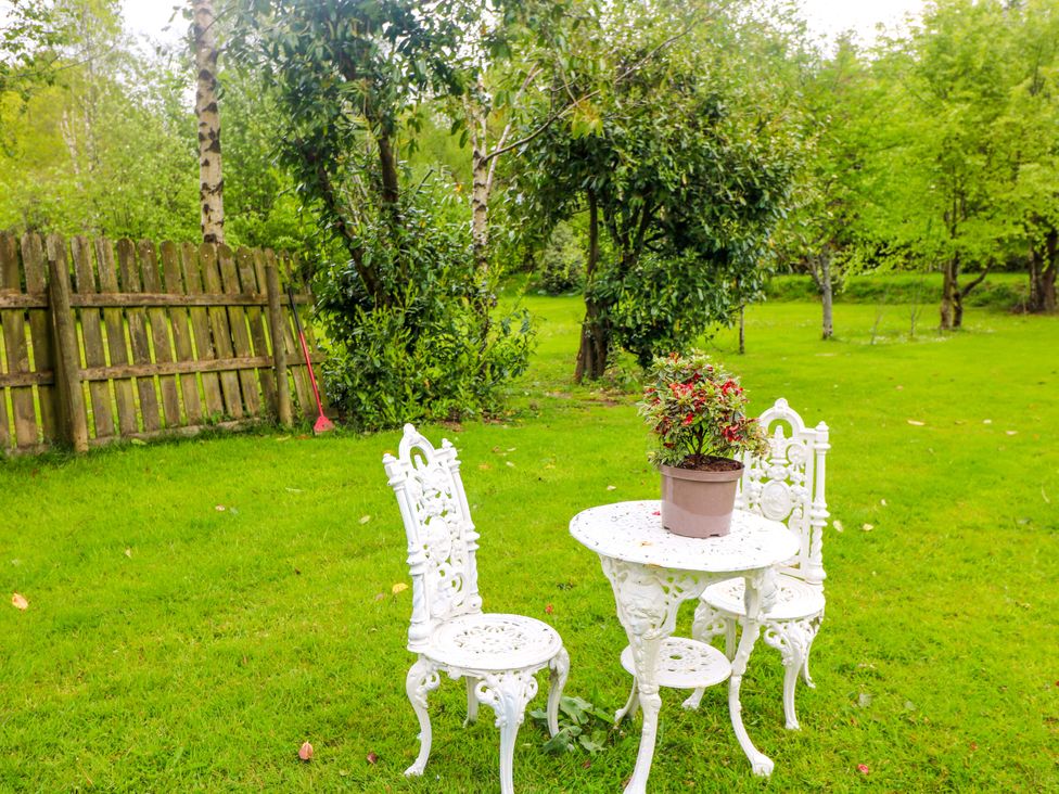 A garden with a table and two chairs beside a flower pot at The Mews @ Derrybawn Laragh, County Wicklow