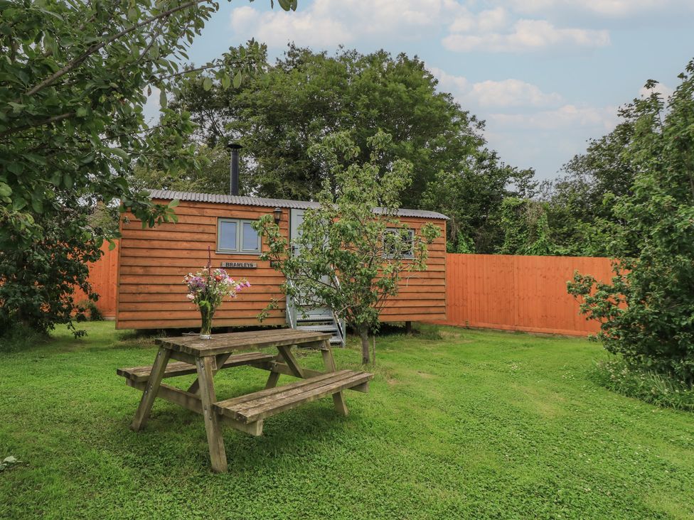 A garden with a cabin and a picnic table at Bramleys in Williton
