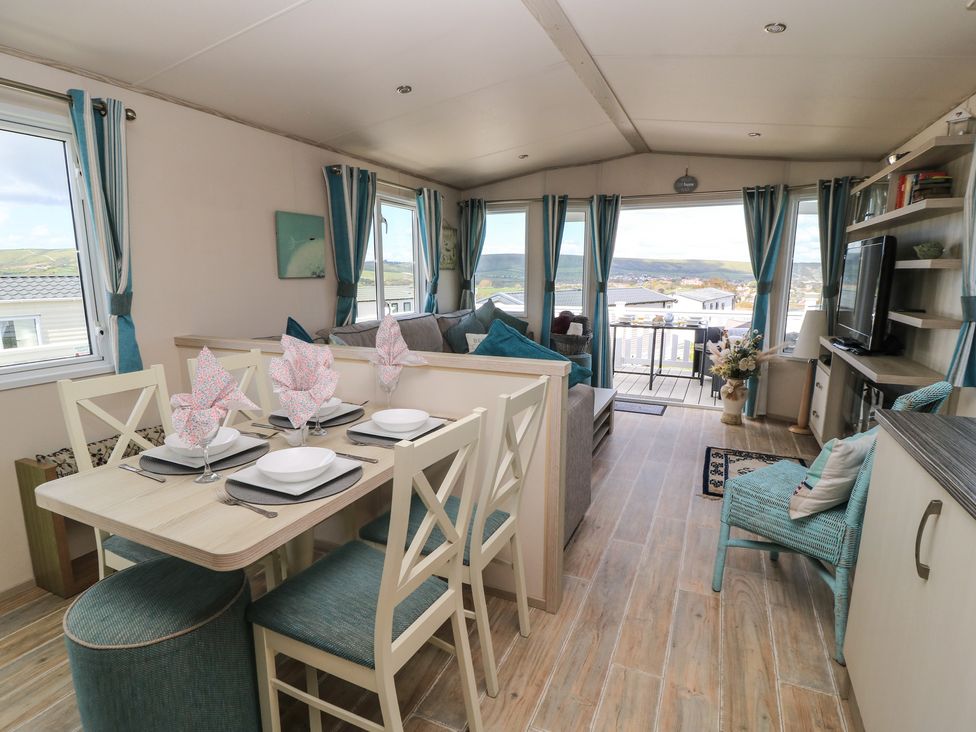 A living room with a dining area and windows offering a view at Swanny View in Swanage