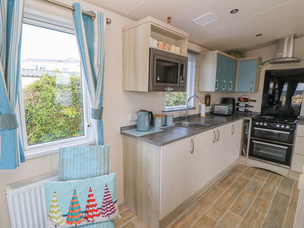 A kitchen with a sink and kitchen appliances at Swanny View in Swanage