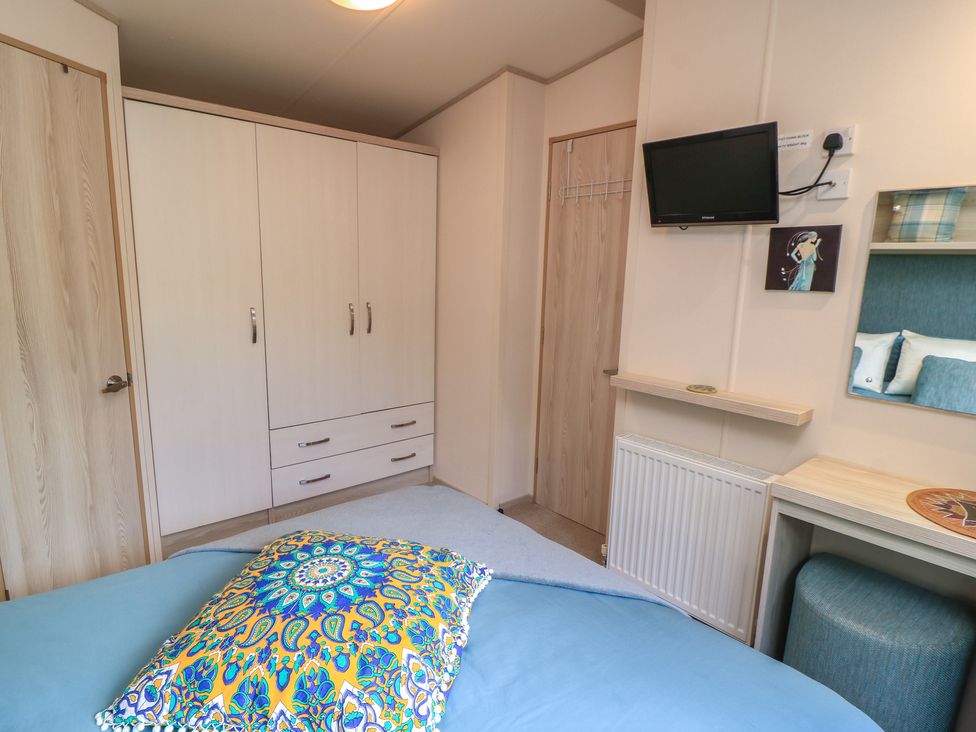 A bedroom with a wardrobe and television at Swanny View in Swanage