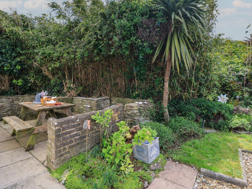 A garden with seating area and plants at Swanny View in Swanage