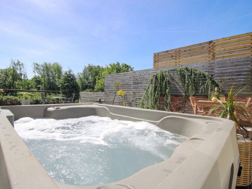 A hot tub with plants and outdoor furniture at Thyme Away in Bucknell