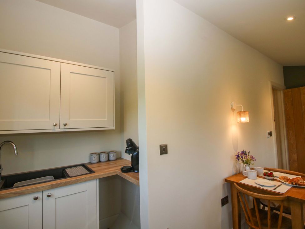 A kitchen with cabinets, sink, coffee machine, and table at Thyme Away in Bucknell
