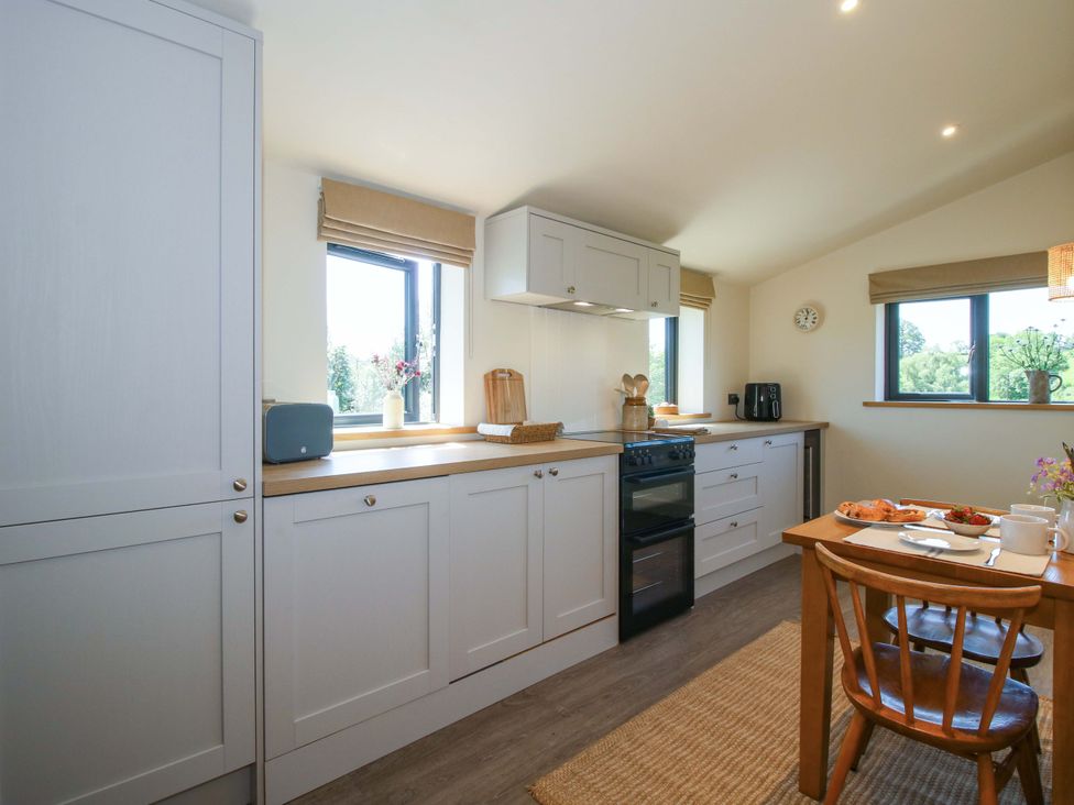 A kitchen with window, cabinets, stove, table and chairs at Thyme Away in Bucknell