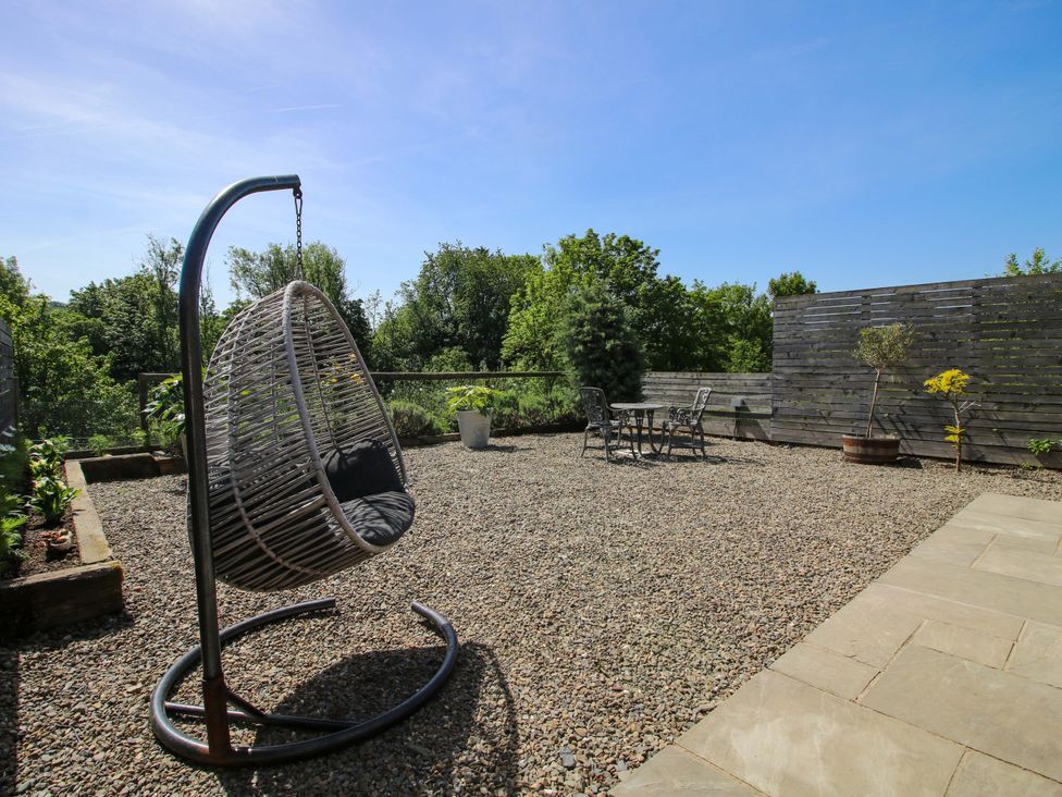 A terrace with a hanging chair and a table with chairs at Thyme Away in Bucknell