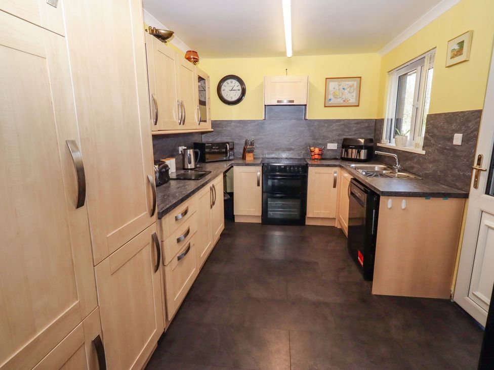 A kitchen with cabinets, oven, sink, and countertop at Willow cottage in Seahouses