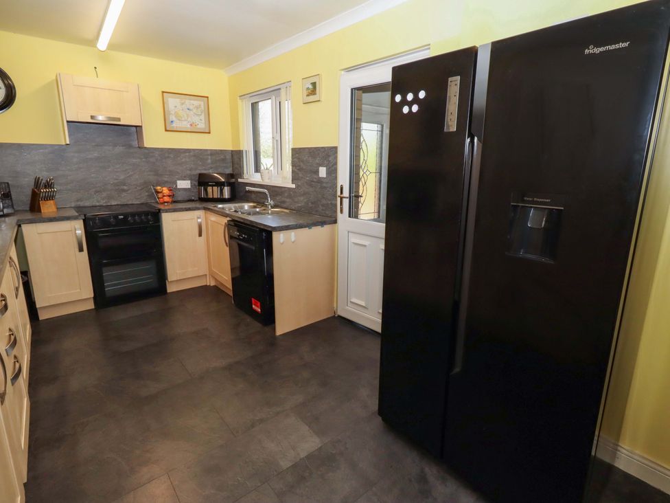 A kitchen with appliances and a doorway at Willow cottage Seahouses