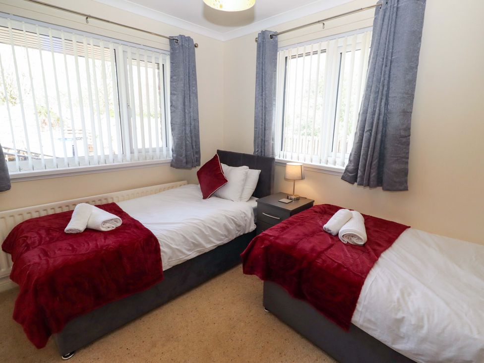 A bedroom with two beds and a bedside table at Willow cottage in Seahouses